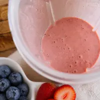 Blended pink yoghurt and berry mixture in a blender cup